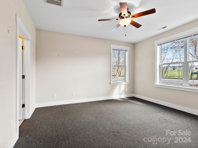 carpeted spare room featuring ceiling fan and a healthy amount of sunlight