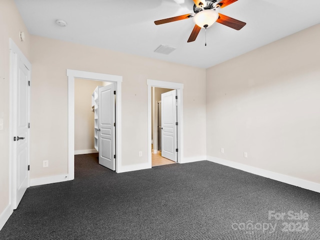 unfurnished bedroom with carpet flooring, ceiling fan, a spacious closet, and a closet