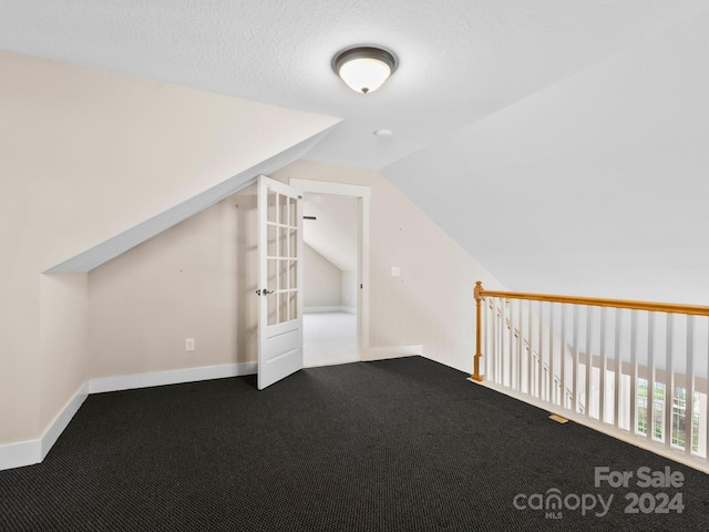 bonus room with carpet floors, a textured ceiling, and vaulted ceiling