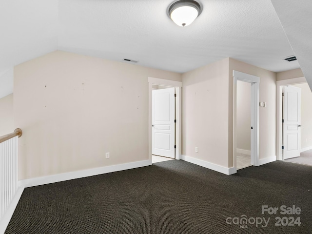 spare room featuring carpet, lofted ceiling, and a textured ceiling