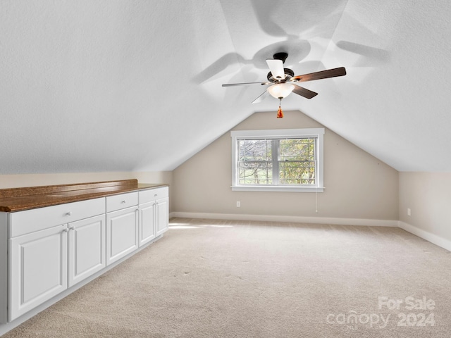 additional living space with a textured ceiling, ceiling fan, lofted ceiling, and light carpet