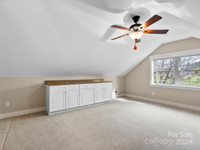 additional living space with ceiling fan, light colored carpet, and vaulted ceiling