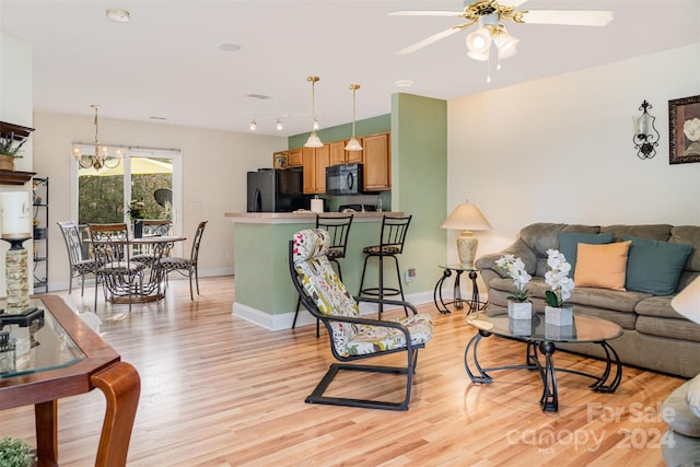 living room featuring light hardwood / wood-style flooring and ceiling fan with notable chandelier