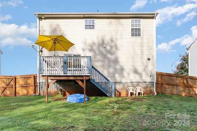 back of property with a lawn and a wooden deck