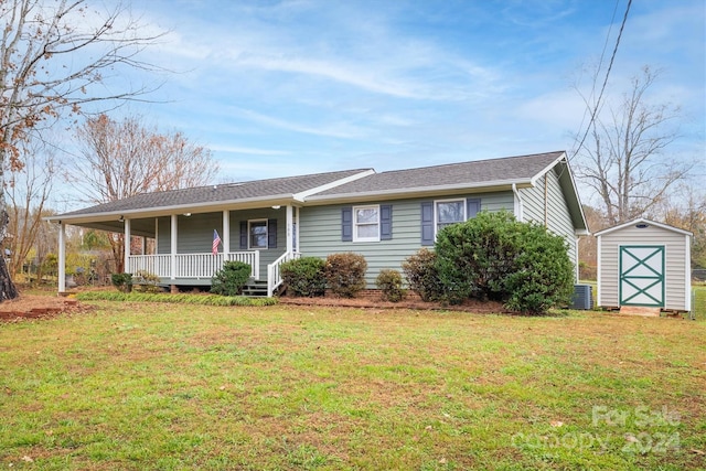 view of front of property featuring cooling unit, a front lawn, covered porch, and a storage shed