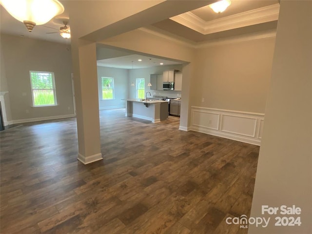 unfurnished living room featuring ceiling fan, dark hardwood / wood-style flooring, ornamental molding, and sink