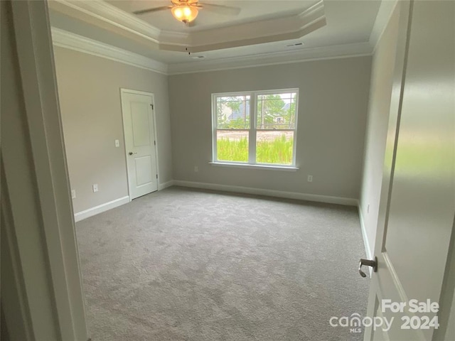 empty room featuring ceiling fan, crown molding, light carpet, and a tray ceiling