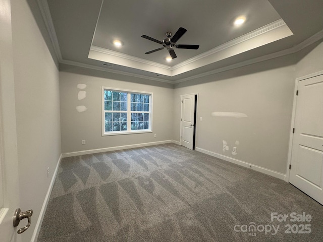 spare room with ceiling fan, ornamental molding, a raised ceiling, and carpet floors