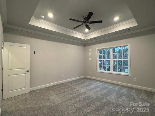 carpeted spare room with a raised ceiling, crown molding, and ceiling fan