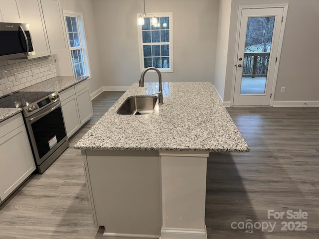 kitchen featuring stainless steel appliances, a kitchen island with sink, sink, and white cabinets