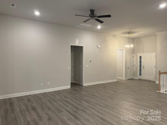 spare room featuring dark hardwood / wood-style floors and ceiling fan with notable chandelier