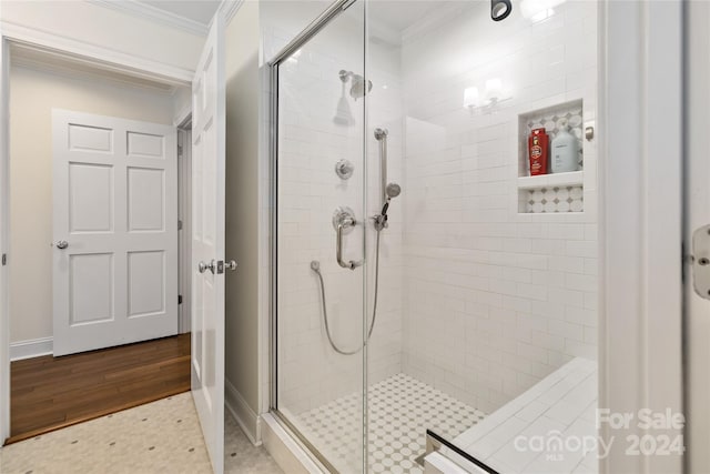 bathroom with hardwood / wood-style floors, a shower with door, and ornamental molding