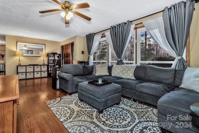 living room with a textured ceiling, ceiling fan, and dark hardwood / wood-style floors