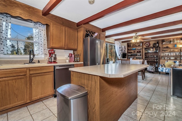 kitchen featuring beam ceiling, ceiling fan, a center island, and stainless steel appliances