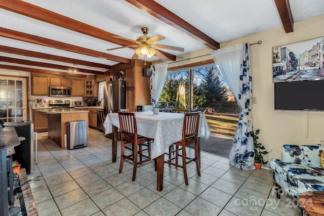 tiled dining area featuring ceiling fan and beamed ceiling