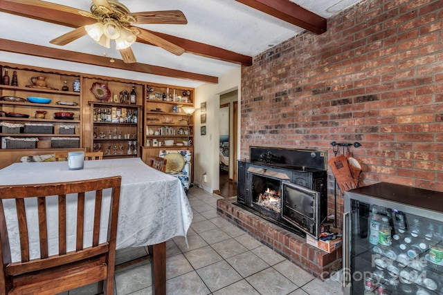 tiled dining area with brick wall, ceiling fan, beverage cooler, beam ceiling, and a fireplace