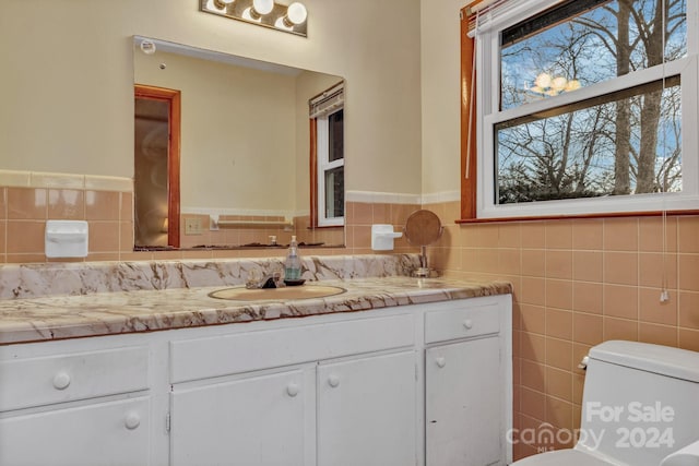 bathroom featuring vanity, toilet, and tile walls