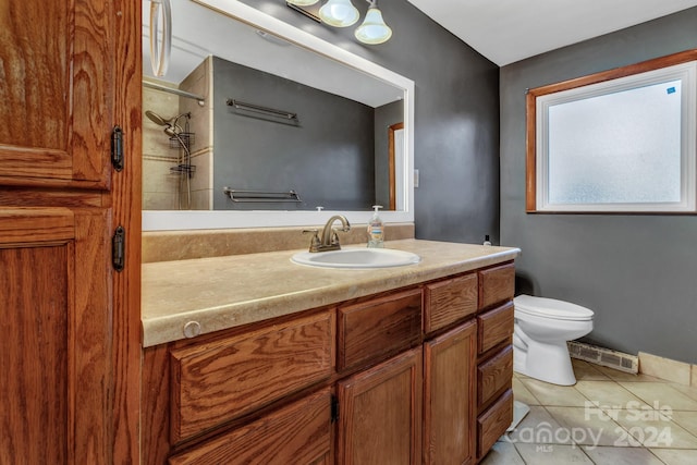 bathroom with tile patterned floors, vanity, tiled shower, and toilet