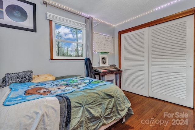 bedroom with wood-type flooring, a textured ceiling, and a closet