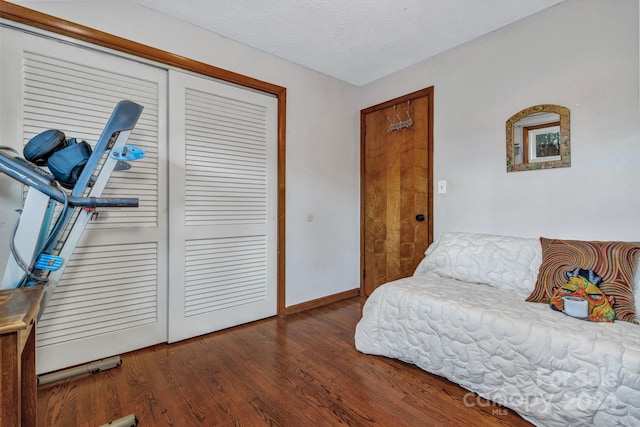 bedroom featuring a closet, dark wood-type flooring, and a textured ceiling