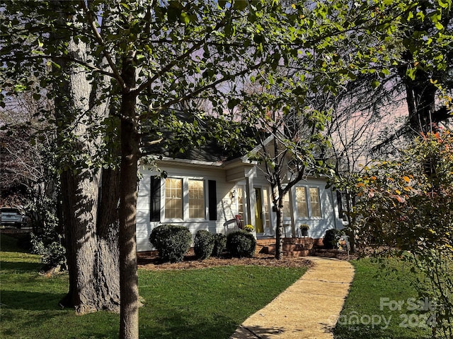 view of property hidden behind natural elements featuring a front yard