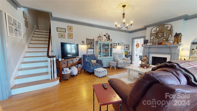 living room with hardwood / wood-style floors, an inviting chandelier, ornamental molding, and a brick fireplace