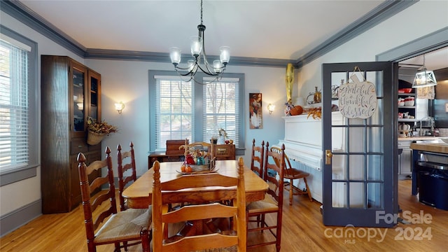 dining area featuring crown molding, an inviting chandelier, and light wood-type flooring