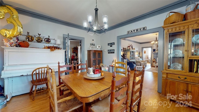 dining area with light hardwood / wood-style floors, ornamental molding, and a notable chandelier