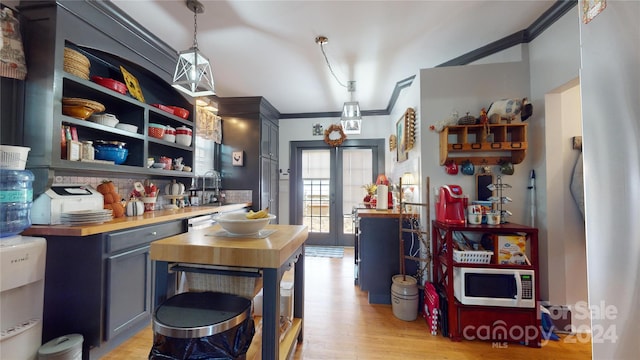 kitchen featuring french doors, hanging light fixtures, butcher block countertops, crown molding, and light hardwood / wood-style floors