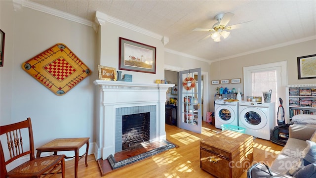 living room featuring washer and clothes dryer, light hardwood / wood-style floors, crown molding, and a fireplace