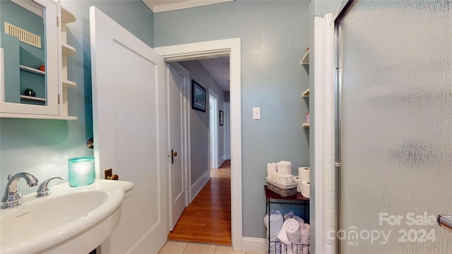 bathroom featuring wood-type flooring, a shower with shower door, and sink