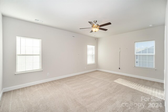 carpeted empty room featuring ceiling fan and a healthy amount of sunlight