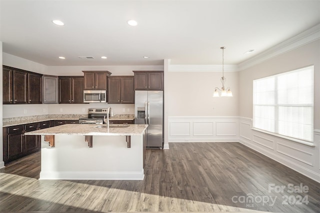 kitchen featuring dark hardwood / wood-style floors, sink, appliances with stainless steel finishes, and a breakfast bar area