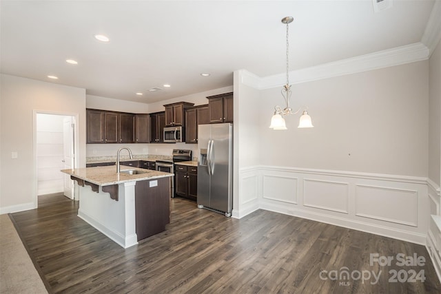 kitchen with appliances with stainless steel finishes, dark hardwood / wood-style floors, decorative light fixtures, and a breakfast bar area