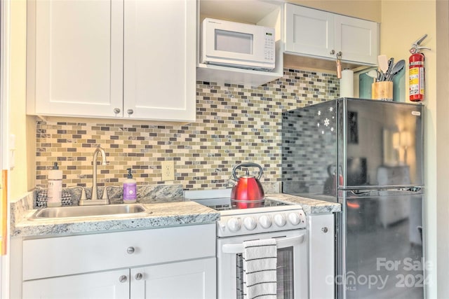 kitchen featuring decorative backsplash, light stone counters, white appliances, sink, and white cabinetry