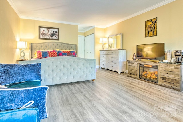 bedroom featuring a fireplace, hardwood / wood-style floors, a closet, and crown molding