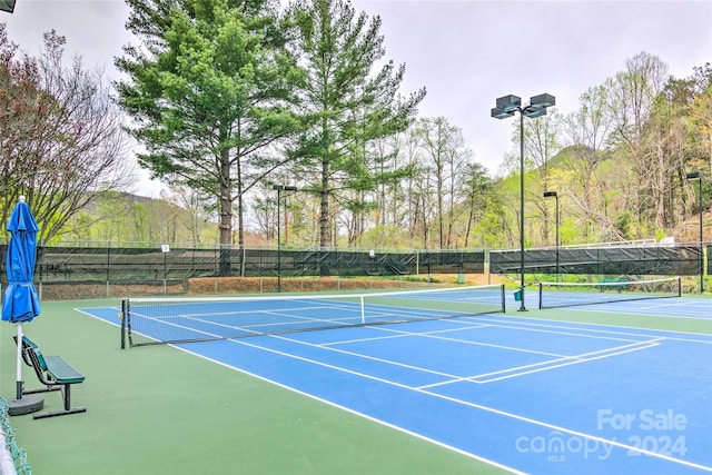 view of tennis court featuring basketball hoop and a mountain view