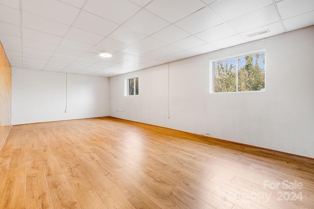 unfurnished room featuring a drop ceiling, a healthy amount of sunlight, and light wood-type flooring