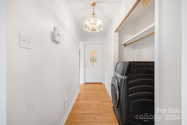 laundry room featuring washer and clothes dryer, an inviting chandelier, and light wood-type flooring