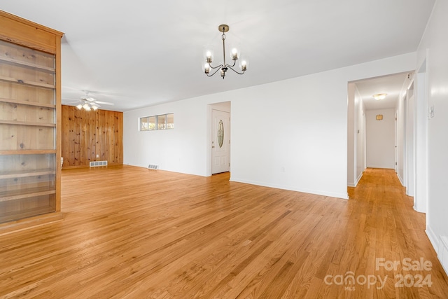 unfurnished living room featuring ceiling fan with notable chandelier and light hardwood / wood-style floors