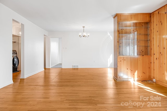 interior space featuring washer / clothes dryer, wood walls, a chandelier, and light wood-type flooring