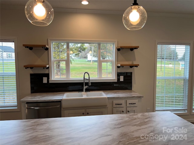 kitchen featuring stainless steel dishwasher, a wealth of natural light, sink, pendant lighting, and white cabinets