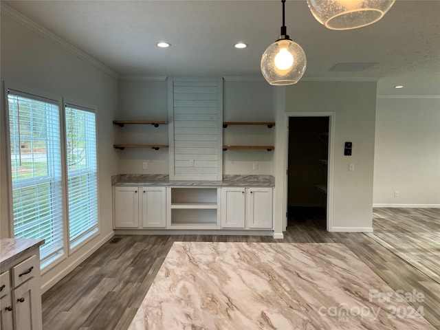 kitchen featuring light stone countertops, crown molding, dark wood-type flooring, pendant lighting, and white cabinets