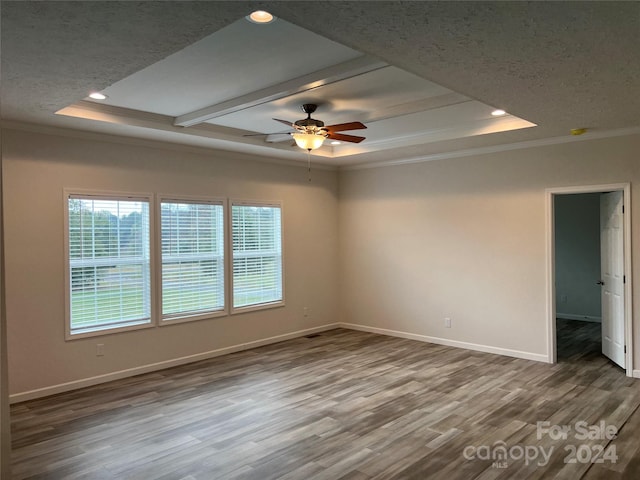 spare room with a raised ceiling, wood-type flooring, and ornamental molding