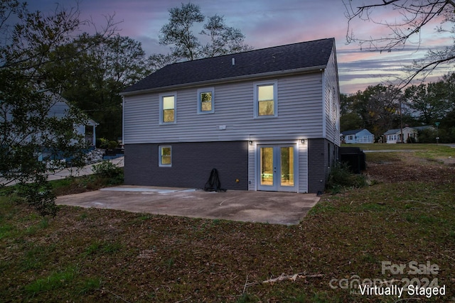 back house at dusk featuring a patio area