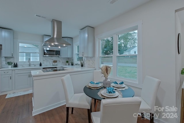 kitchen featuring backsplash, white cabinets, wall chimney range hood, dark hardwood / wood-style flooring, and gas cooktop