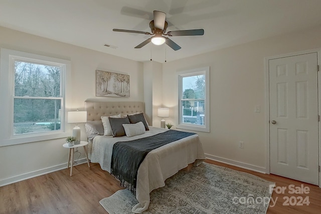 bedroom with ceiling fan, light wood-type flooring, and multiple windows