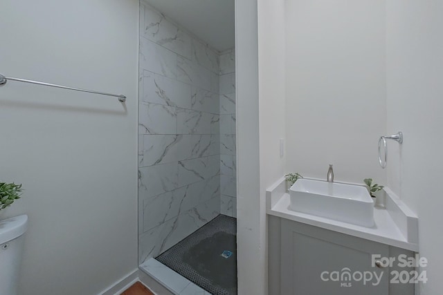 bathroom featuring vanity, toilet, and tiled shower