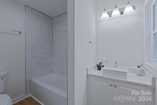 full bathroom with vanity, hardwood / wood-style flooring, toilet, and tiled shower / bath