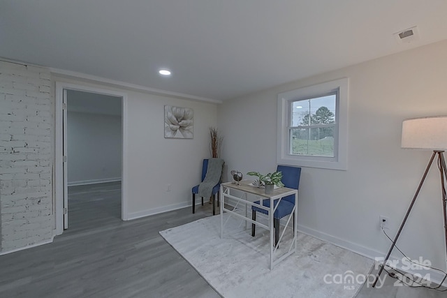 living area with wood-type flooring and brick wall